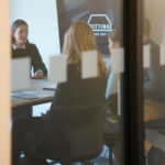 Geschäftsleute bei Meeting in moderner Besprechungsecke, Blick durch Glasscheibe.