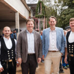 Vier Männer in festlicher Tracht und Businesskleidung bei einem Fest.