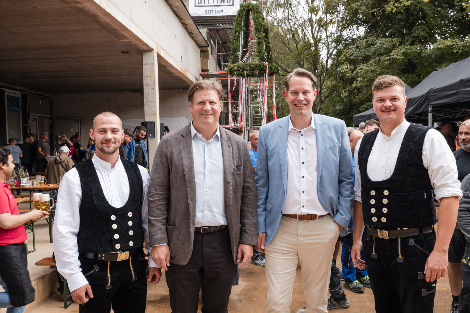 Vier Männer in festlicher Tracht und Businesskleidung bei einem Fest.
